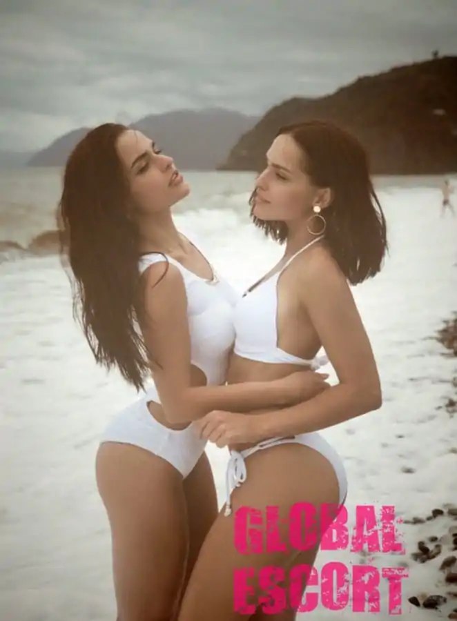 Escort Sexy twin sisters posing in white swimsuits on the sea.